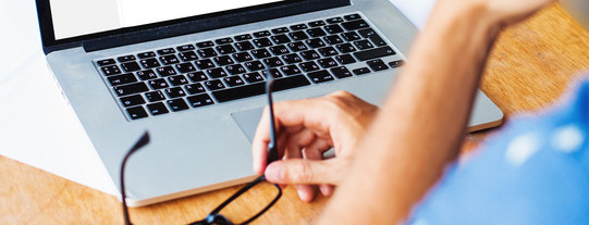 Studierende sitzt am Arbeitsplatz und schaut auf den Laptop.